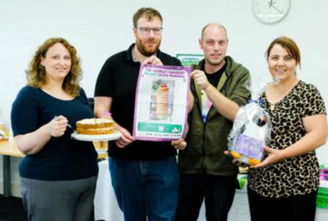 4 team members holding a certificate and a cake