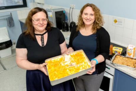 2 people holding a tray of lasagne