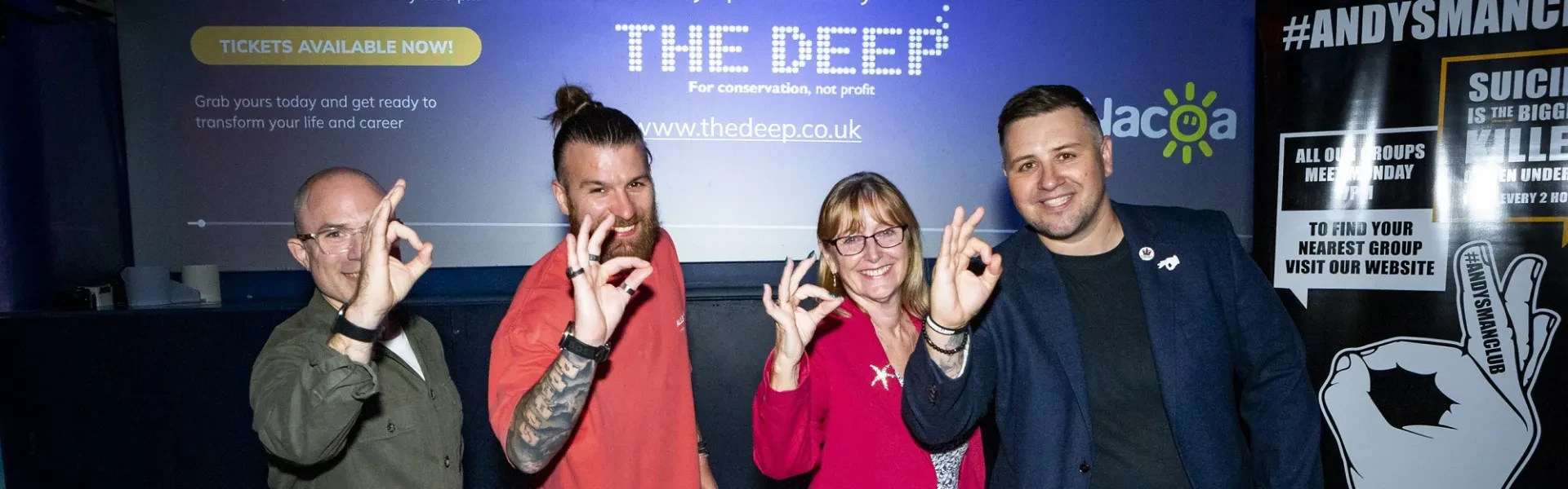 The team from Think Cloud stood smiling and posing with Freya, Head of Business and Corporate, in front of the stage in The Deep's Endless Ocean area.